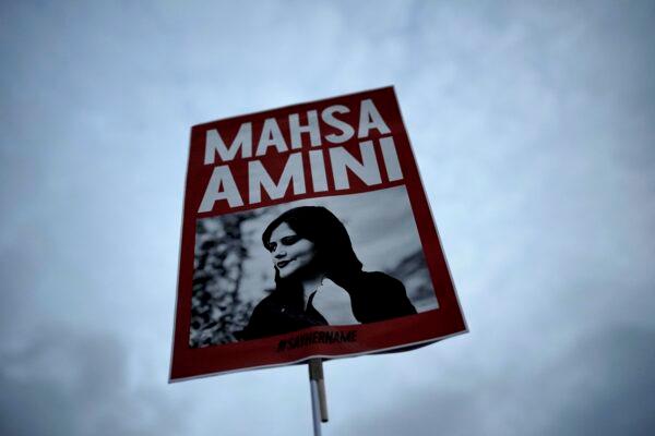 A placard with a picture of Mahsa Amini, a young Iranian woman who died in police custody, is held high at a protest in Berlin on Sept. 28, 2022. (Markus Schreiber/AP Photo)