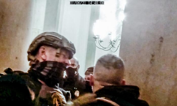 An Oath Keepers member gets in between an unknown protester and Capitol Police officer Harry Dunn during a tense exchange in the Small House Rotunda on Jan. 6, 2021. (Stephen Horn/Screenshot via The Epoch Times)