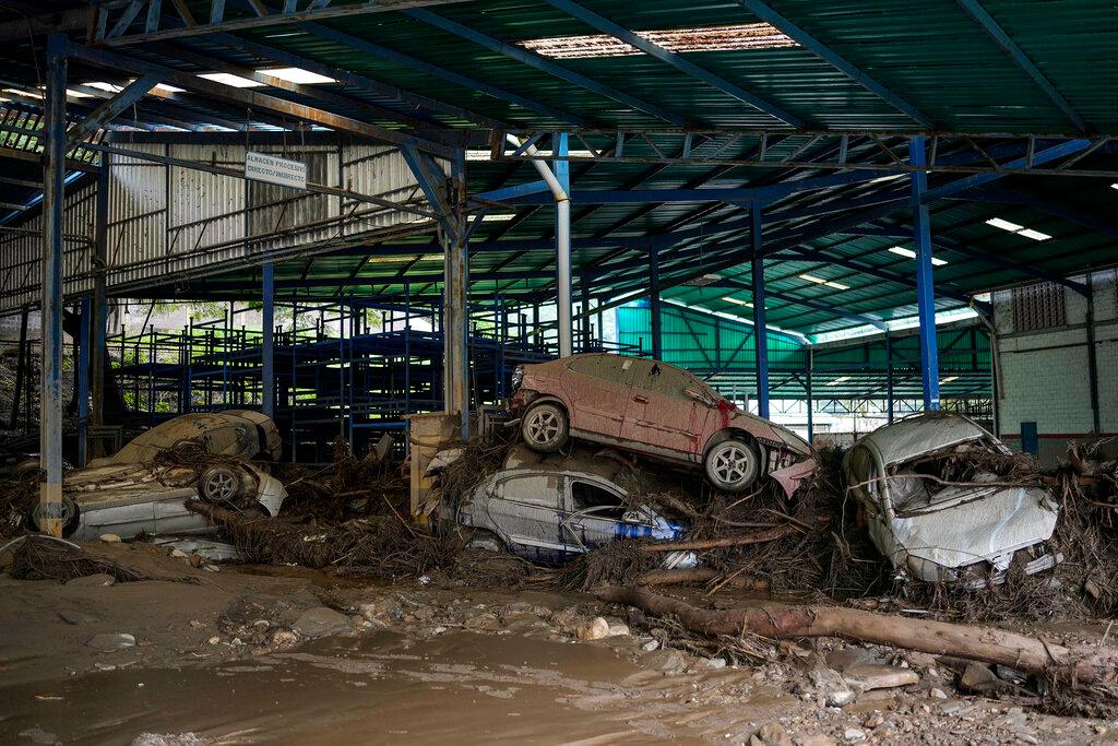 Cars are piled up in a workshop after intense rains caused flash flooding and overflowed Las Tejerias river in Las Tejerias, Venezuela, on Oct. 9, 2022. (Matias Delacroix/AP Photo)