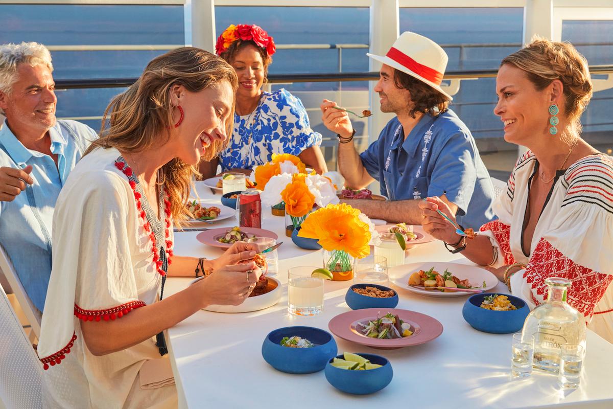 A group of friends have a private dinner party on the terrace aboard a Virgin Voyages ship. (Virgin Voyages)