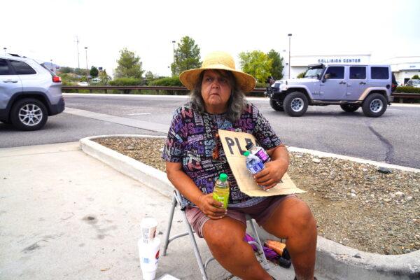 Catherine Schwab sits near the main entrance to Walmart in Cottonwood, Ariz., on Oct. 3. Schwab said she panhandles almost daily to raise the money she needs to drive home to Michigan. (Allan Stein/The Epoch Times)