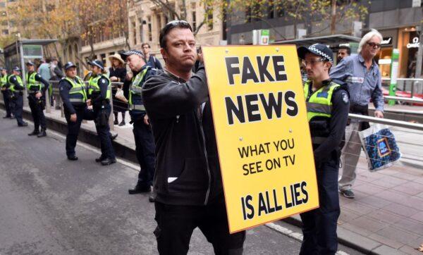 A man holds up a "Fake News" placard outside the British consulate in Melbourne, Australia, on June 9, 2018. (William West/AFP via Getty Images)