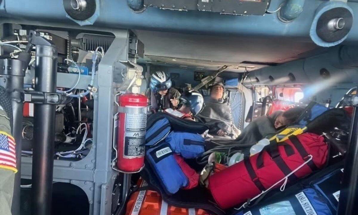 A Coast Guard Air Station New Orleans MH-60 Jayhawk aircrew treats three rescued boaters for injuries, approximately 25 miles offshore from Empire, La., on Oct. 9, 2022. (Coast Guard Air Station New Orleans)