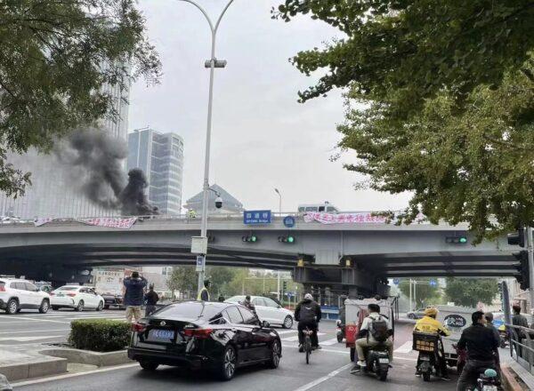 People take pictures of rare banners of political protest from an overpass in Beijing on Oct. 13, 2022. (Screenshot of Fangshimin’s Twitter account via The Epoch Times)