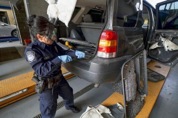 A U.S. Customs and Border Protection agent searches an automobile for contraband in the line to enter the United States at the San Ysidro Port of Entry in San Ysidro, Calif., on Oct. 2, 2019. (Sandy Huffaker/AFP via Getty Images)