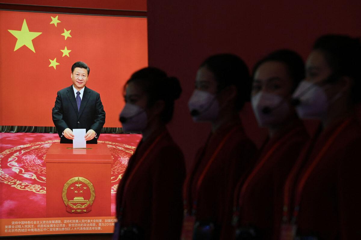 Attendants stand near a picture of CCP leader Xi Jinping during an exhibition that showed the country's achievements during Xi's past two terms in office, in Beijing, Oct. 12, 2022, ahead of the 20th National Congress. (Noel Celis/AFP via Getty Images)