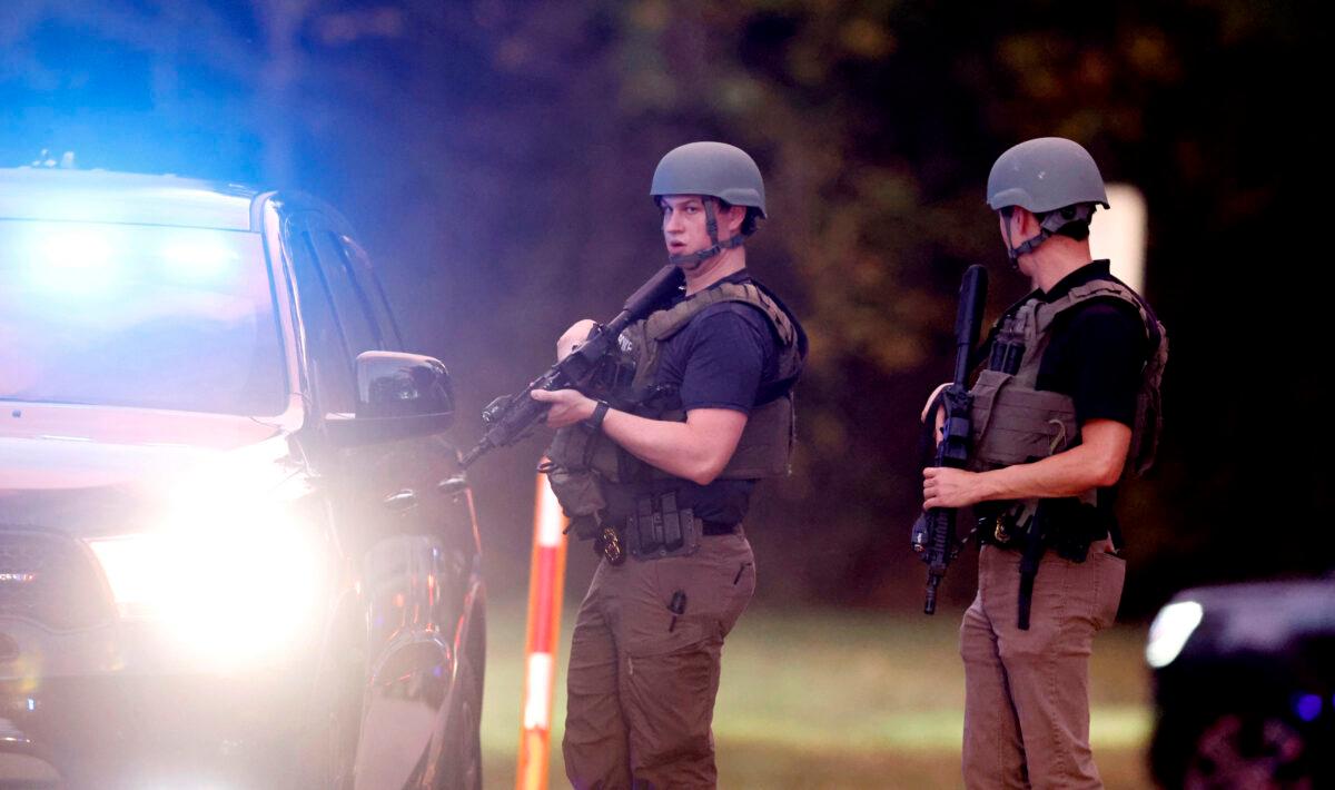 Law enforcement stand at the entrance to Neuse River Greenway Trail parking at Abington Lane following a shooting in Raleigh, N.C., on Oct. 13, 2022. (Ethan Hyman/The News & Observer via AP)