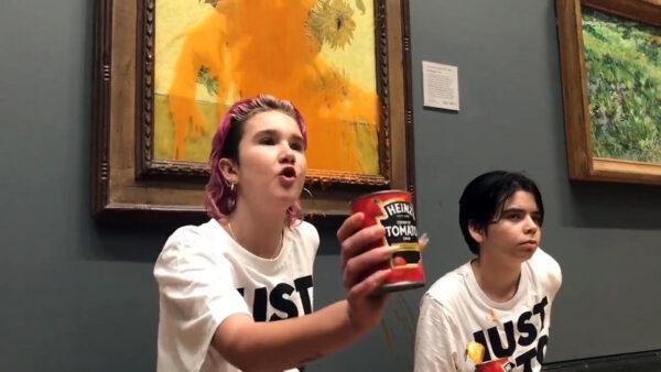 Handout photo issued by Just Stop Oil of two protesters who have thrown tinned soup at Vincent Van Gogh's 1888 work Sunflowers at the National Gallery in London, on Oct. 14, 2022. (PA Media/Just Stop Oil)