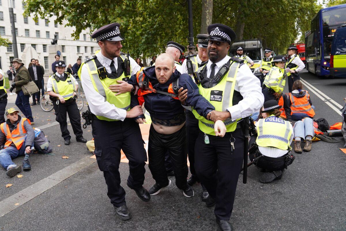 Police officers detain a Just Stop Oil protester outside New Scotland Yard in London on Oct. 14, 2022. (Stefan Rousseau/PA Media)