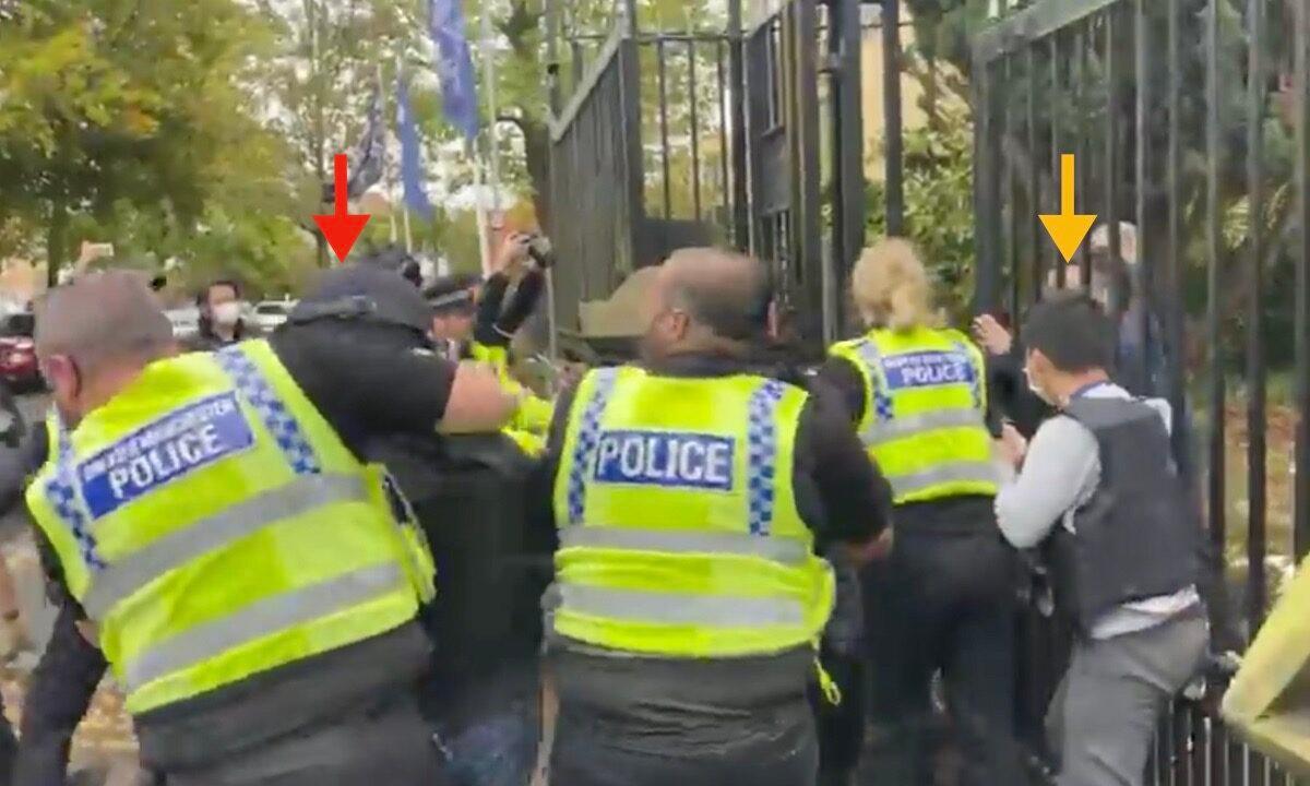 Outside the Chinese Consulate, the CCP staff walked outside the gate to try to steal the poster from the protesters. The yellow arrow points to the guy who lost his helmet. The red arrow points to the CCP staff who was being pulled aside by the British police. (Screenshot of video)