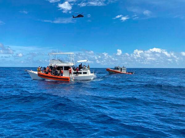 Coast Guard law enforcement crews aid people from an unsafe and overloaded 40-foot cabin cruiser about 20 miles off Boca Raton, Fla., on Oct. 12, 2022. (U.S. Coast Guard via AP)