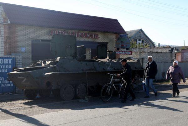 Local residents walk past a destroyed Russian personnel armored carrier in the town of Kupiansk, in the Kharkiv region of Ukraine, on Oct. 17, 2022, amid the Russian military invasion. (Anatolii Stepanov/AFP via Getty Images)