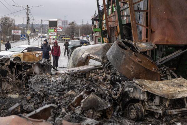People walk past a destroyed Russian military vehicle at a frontline position in Irpin, Ukraine, on March 3, 2022. (Chris McGrath/Getty Images)