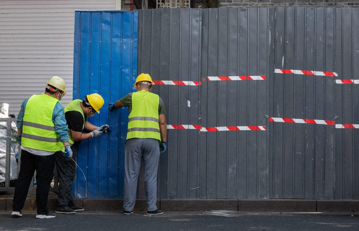 Workers erect a barrier fence around local residences and shops in lockdown after new local cases of COVID-19 were found in the Sanlitun shopping district in Beijing, China, on June 23, 2022. (Kevin Frayer/Getty Images)