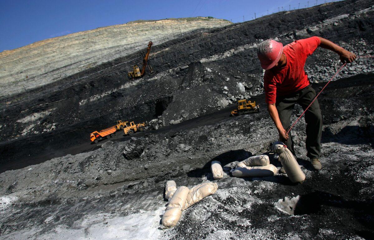 A coal miner works on coal seams in an open pit coal mine in Chifeng of Inner Mongolia Autonomous Region, China, on Aug. 19, 2006. (China Photos/Getty Images)