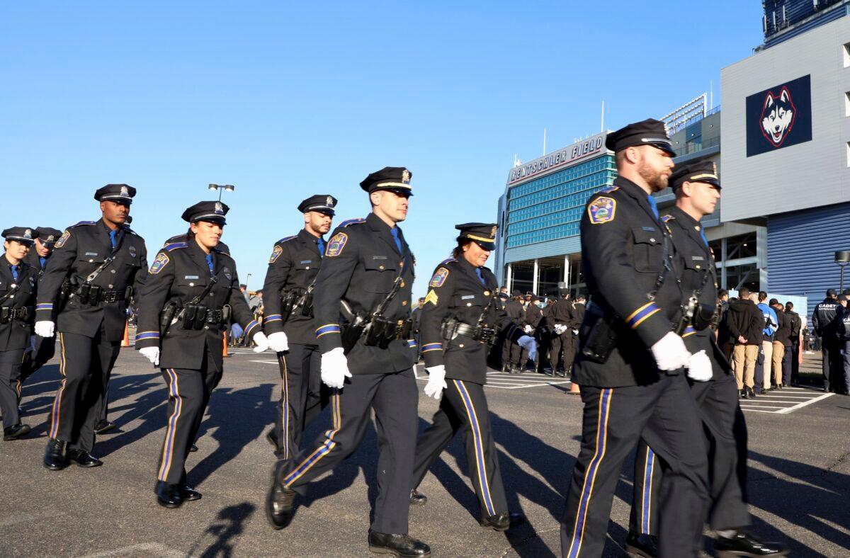 Police officers file into Pratt & Whitney Stadium at Rentschler Field for a funeral service for Bristol Police officers Dustin DeMonte and Alex Hamzy in East Hartford, Conn., on Oct. 21, 2022. (Sean Fowler/Hartford Courant via AP)