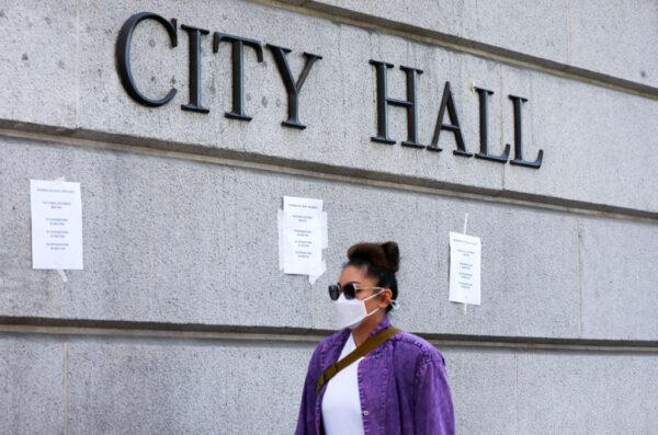 A person walks past signs posted outside City Hall calling for the resignations of L.A. City Councilors Kevin de León and Gil Cedillo in the wake of a leaked audio recording in Los Angeles, on Oct. 18, 2022. (Mario Tama/Getty Images)