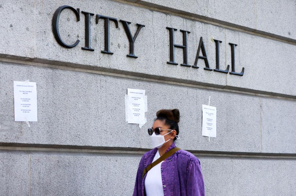 A person walks past signs posted outside City Hall calling for the resignations of city councilors in the wake of a leaked audio recording in Los Angeles on Oct. 18, 2022. (Mario Tama/Getty Images)