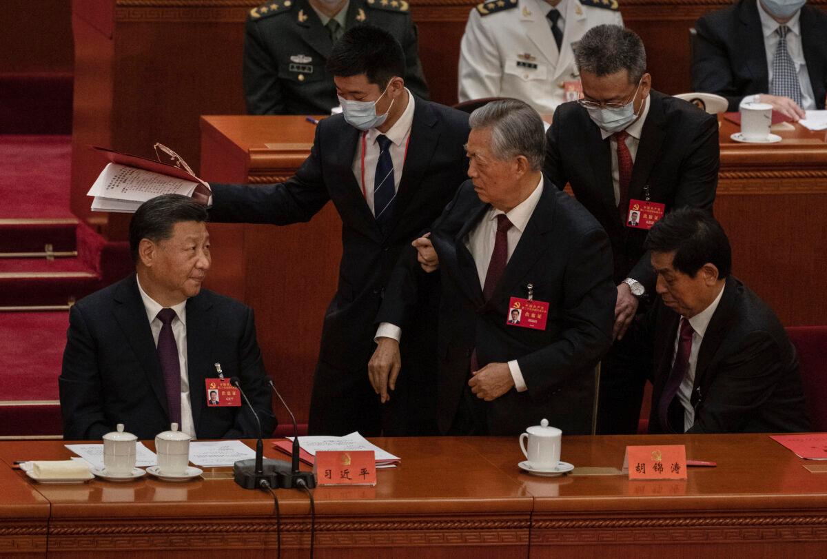 Chinese President Xi Jinping (L) looks on as former President Hu Jintao is helped to leave early from the closing session of the 20th National Congress of the Communist Party of China, at The Great Hall of People in Beijing, on Oct. 22, 2022. (Kevin Frayer/Getty Images)