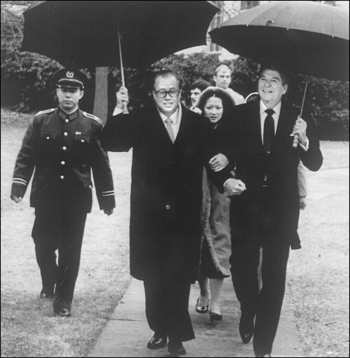 U.S. President Ronald Reagan (R) and Chinese Premier Zhao Ziyang, both holding umbrellas, walk arm in arm, as Reagan escorts him to his car through the rain after a meeting in the Cabinet Room in the White House, in Washington, on Oct. 1, 1984. (AFP/AFP via Getty Images)