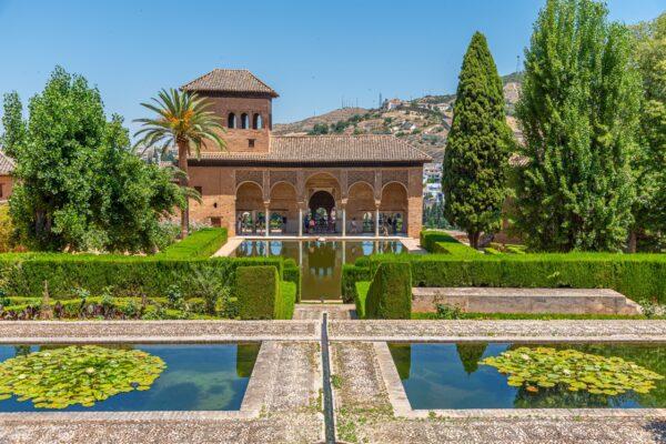 The Partal Palace is one of the oldest structures in the Alhambra. It's also known as the Portico Palace because of the portico formed by the five-arch arcade on the side of the pool. Behind the Moorish structure is a view of charming Granada. (<a href="https://www.shutterstock.com/g/pavel+dudek">trabantos</a>/<a href="https://www.shutterstock.com/image-photo/el-partal-torre-de-las-damas-2038729124">Shutterstock</a>)