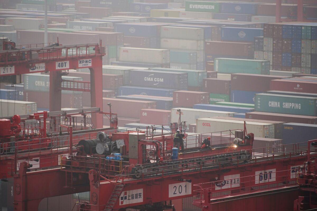 Workers on a crane above containers at the Yangshan Deep Water Port in Shanghai on Jan. 13, 2022. (Aly Song/Reuters)
