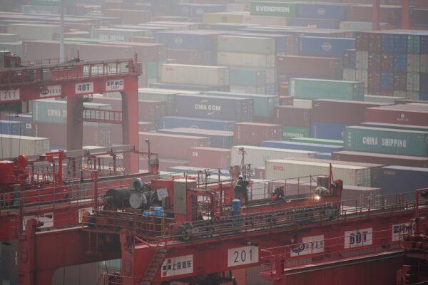 Workers on a crane above containers at the Yangshan Deep Water Port in Shanghai on Jan. 13, 2022. (Aly Song/Reuters)