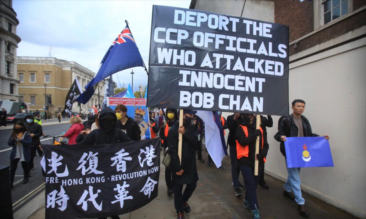 Protesters carry a banner asking for CCP officials that assaulted Bob Chan to be deported, as they march down Whitehall, London, on Oct. 23, 2022. (Martin Pope/Getty Images)