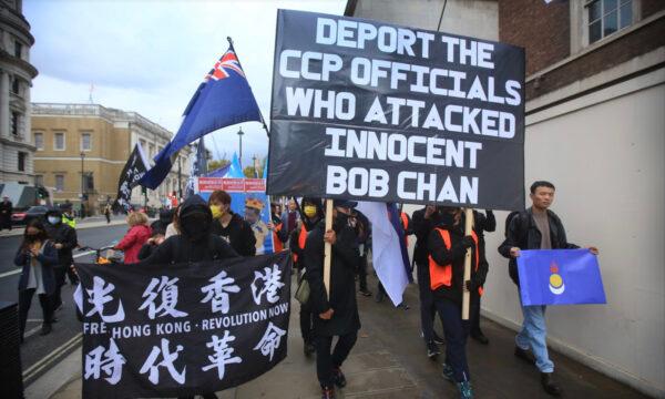 Protesters march down Whitehall, London, England, on Oct. 23, 2022, carrying a banner asking for CCP officials that assaulted Bob Chan to be deported. Bob Chan was dragged into the grounds of the Manchester Consulate and beaten up during a Hong Kong pro-democracy protest on 16 Oct. 2022. (Martin Pope/Getty Images)