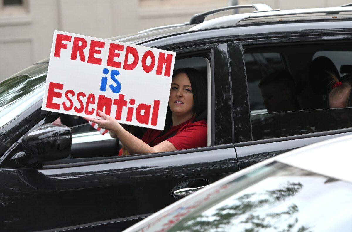 A driver holds up a sign as hundreds of people gather to protest COVID-19 lockdowns at California's state capitol building in Sacramento on April 20, 2020. (Josh Edelson/AFP via Getty Images)
