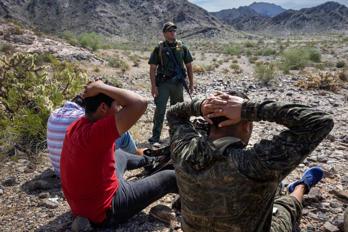 A U.S. Border Patrol agent watches over a group of illegal immigrants after tracking them through rugged terrain at the Organ Pipe National Monument, Ariz., on Sept. 28, 2022. (John Moore/Getty Images)