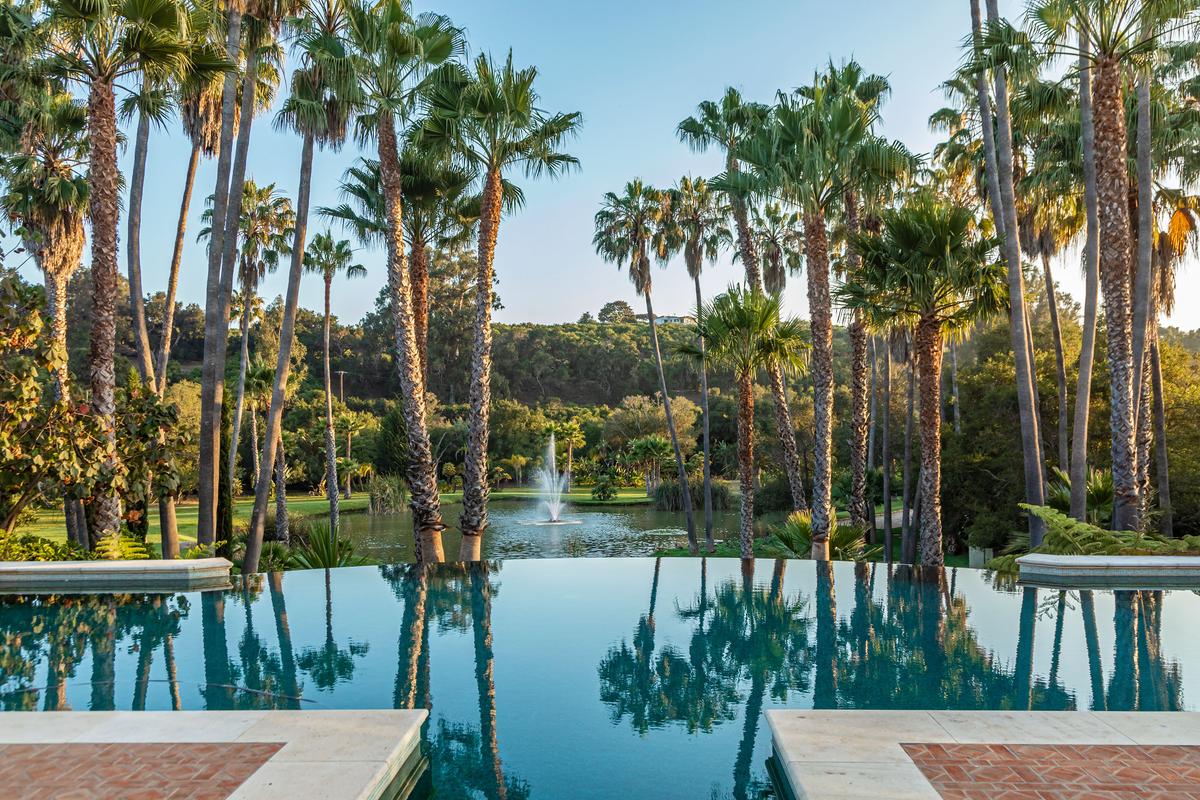 The infinity-edge pool looks out over formal gardens, manicured lawns, a koi pond, fountains, and acres of splendid nature. (Courtesy of Simon Berlyn for Sotheby’s International Realty)