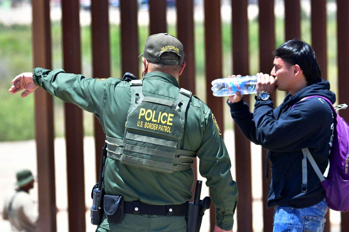 A U.S. Border Patrol agent directs an illegal alien after he crossed into the United States from Mexico through a gap in the border wall separating Algodones, Mexico, from Yuma, Ariz., on May 16, 2022. (Frederic J. Brown/AFP via Getty Images)