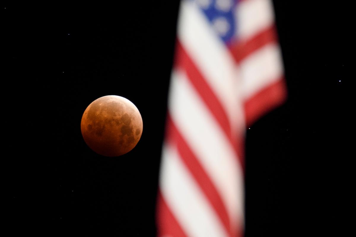 A full moon is seen framed with an American flag during totality of a total lunar eclipse on May 26, 2021, in Chico, California. (PATRICK T. FALLON/AFP via Getty Images)