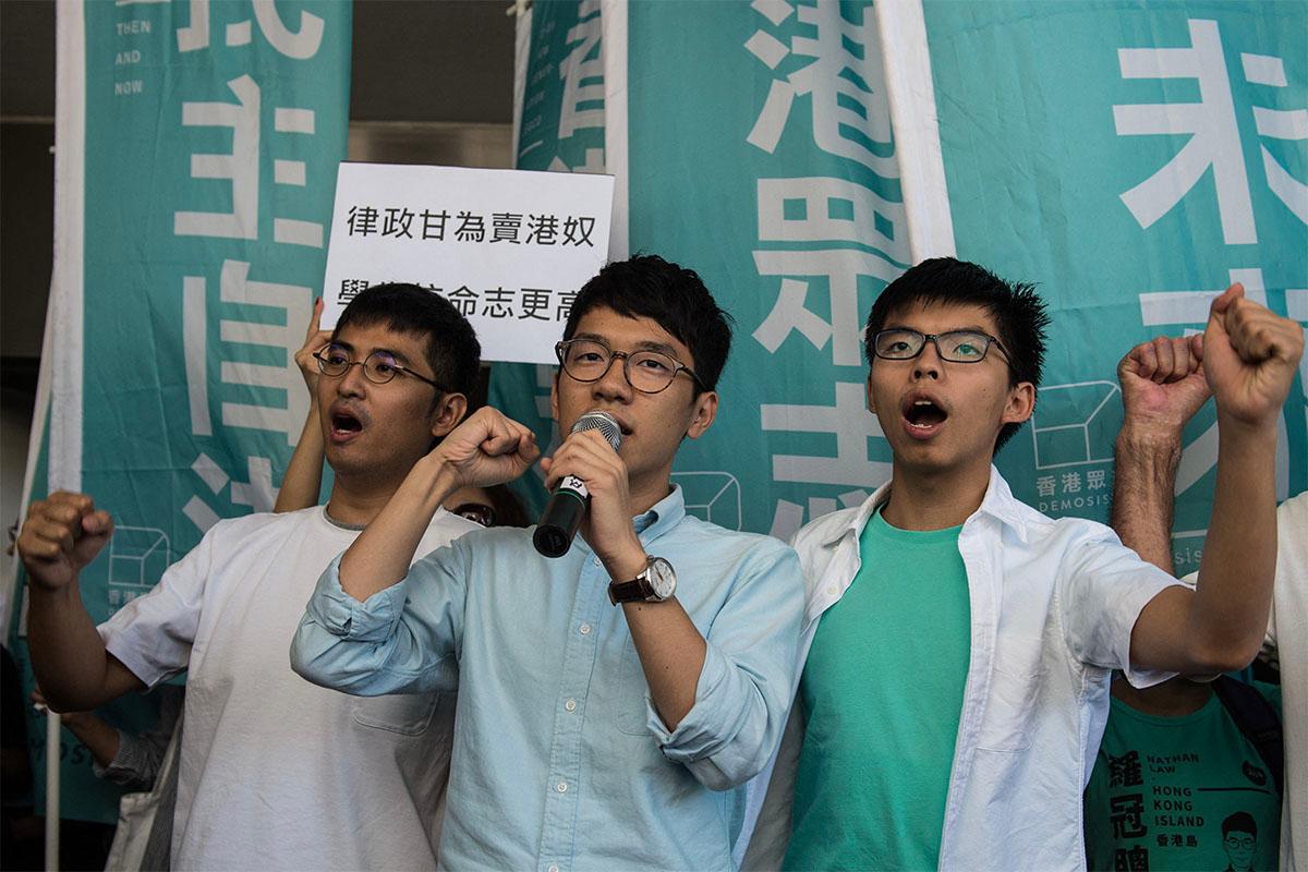 Leaders of Hong Kong's "Umbrella Revolution" Alex Chow (L), newly elected lawmaker Nathan Law (C), and Joshua Wong (R) shout slogans as they arrive at the Eastern Court in Hong Kong on Sept. 21, 2016. The three went to court after prosecutors appealed the sentences handed out over events leading to mass protests in 2014. (Anthony Wallace/AFP)