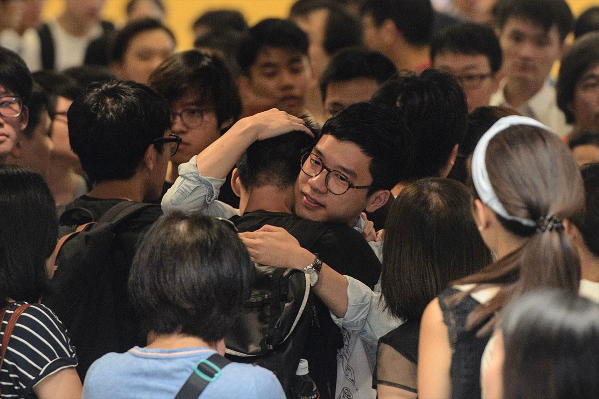 Nathan Law (C) hugs a supporter before his sentencing at the High Court in Hong Kong on Aug. 17, 2017. Umbrella Movement leaders Wong, Law, and Alex Chow were found guilty of unlawful assembly for storming a government forecourt as part of an anti-Beijing protest in 2014. (Anthony Wallace/AFP)