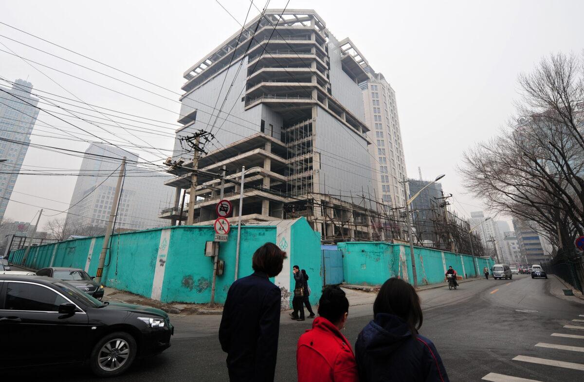 Pedestrians walk past an unfinished building in Beijing on March 18, 2010. (Frederic J. Brown/AFP via Getty Images)