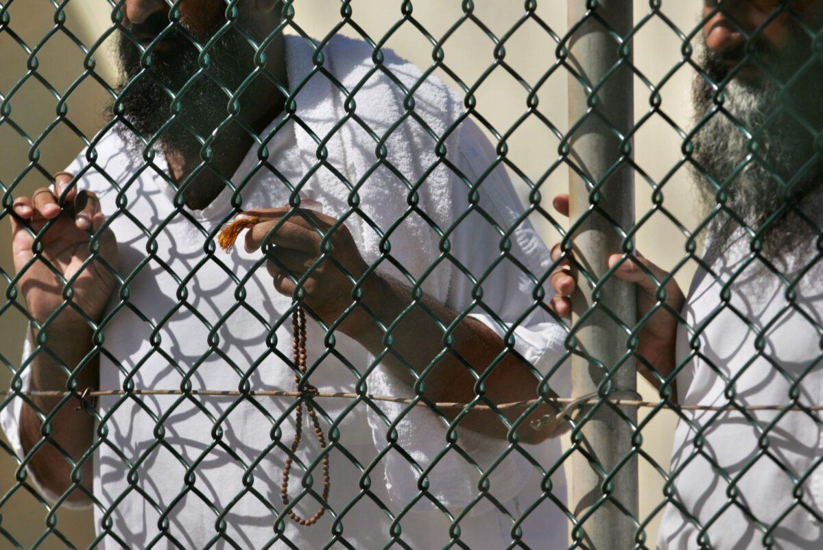 Detainees stand together at a fence at Camp Delta prison at the Guantanamo Bay U.S. Naval Base in Cuba, on Sept. 19, 2006. (Brennan Linsley/AP Photo)