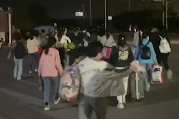 In this photo taken from video footage and released by Hangpai Xingyang, people with suitcases and bags are seen leaving a Foxconn compound in Zhengzhou, Henan Province, on Oct. 29, 2022. (Hangpai Xingyang/Screenshot via AP)