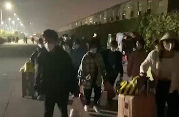 People with suitcases and bags leave Foxconn compound in Zhengzhou in central China's Henan Province on Oct. 29, 2022, in a still from video. (Hangpai Xingyang via AP)
