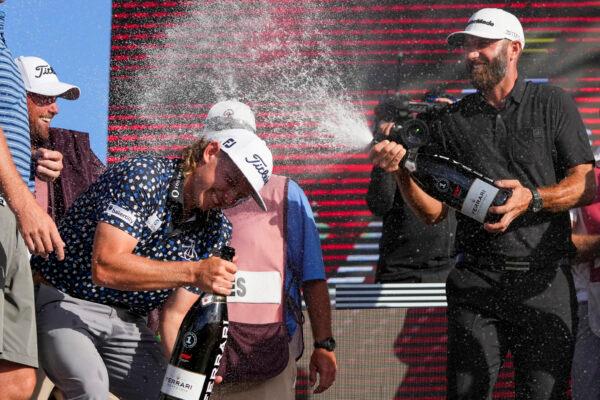 Team Captain Dustin Johnson of 4 Aces GC sprays champagne on Team Captain Cameron Smith of Punch GC on the podium after the team championship stroke-play round of the LIV Golf Invitational—Miami at Trump National Doral, in Doral, Flor., on October 30, 2022. (Eric Espada/Getty Images)