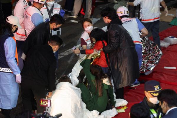 People receive medical help from rescue team members at the scene where dozens of people were injured in a crowd surge during a Halloween festival in Seoul, South Korea, Oct. 29, 2022. (Kim Hong-ji/Reuters)
