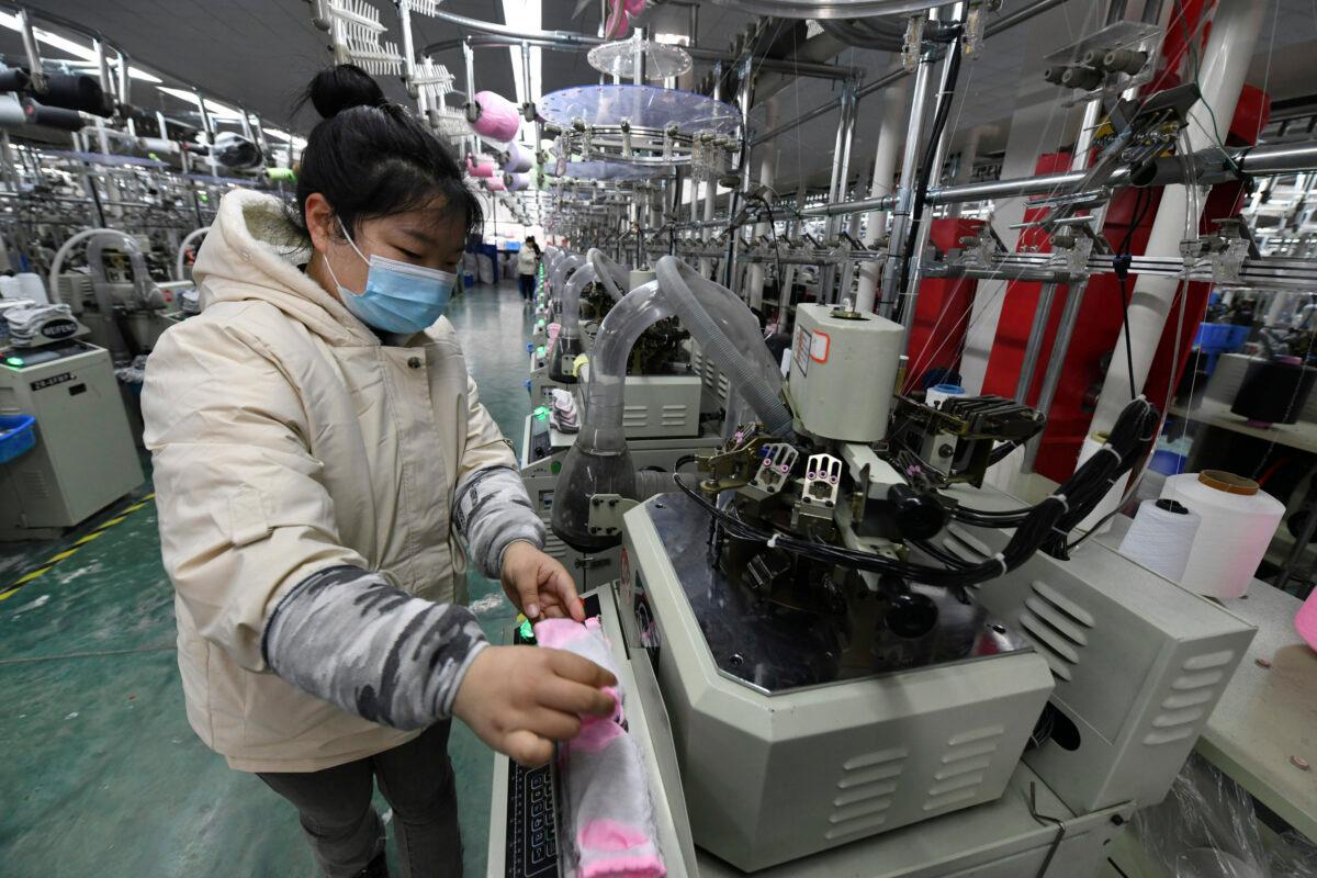 A worker operates a machine for knitting socks in a factory in Funan County in central China's Anhui province on March 1, 2022. (Chinatopix via AP)