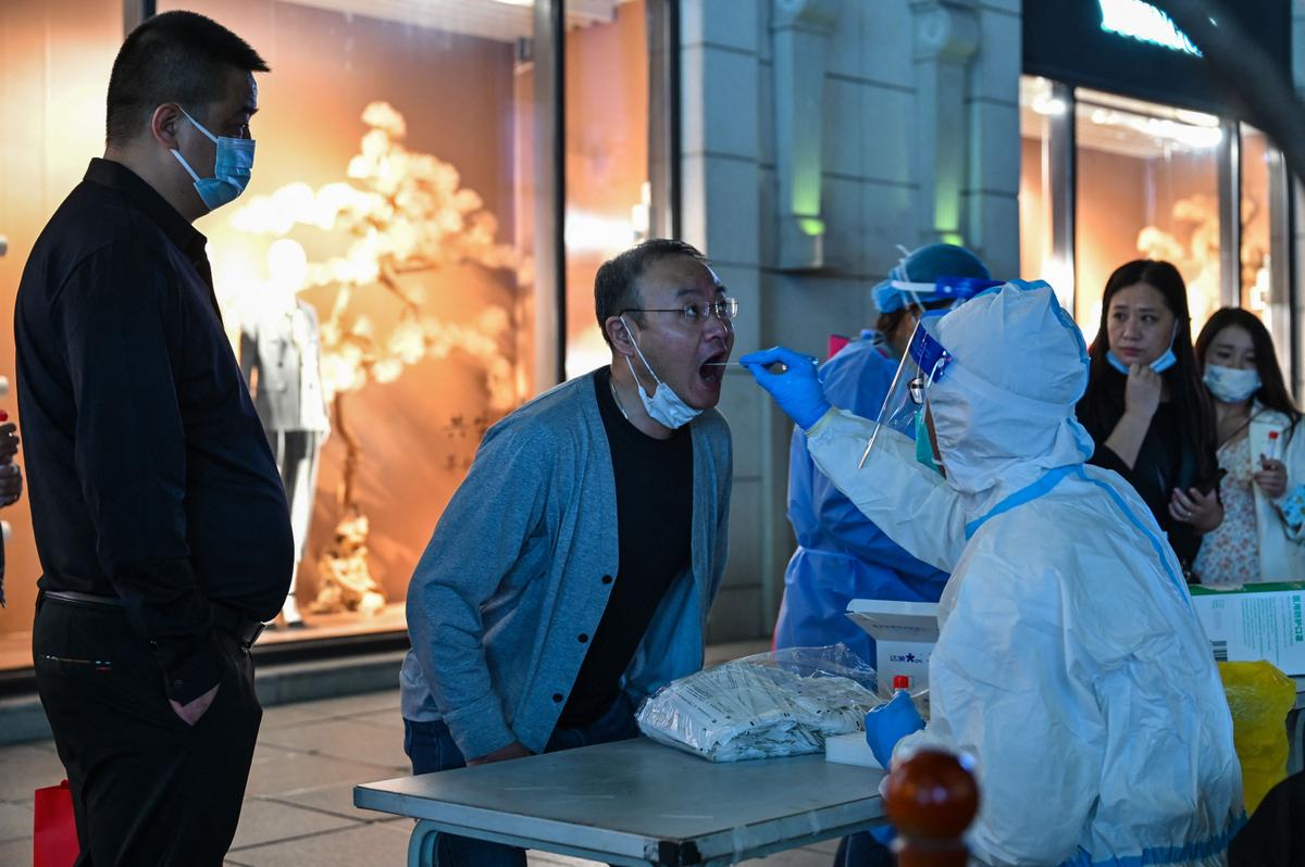 A health worker takes a swab sample from a man to test for the COVID-19 coronavirus in the Huangpu district in Shanghai on Oct. 24, 2022. (Hector Retamal/AFP via Getty Images)