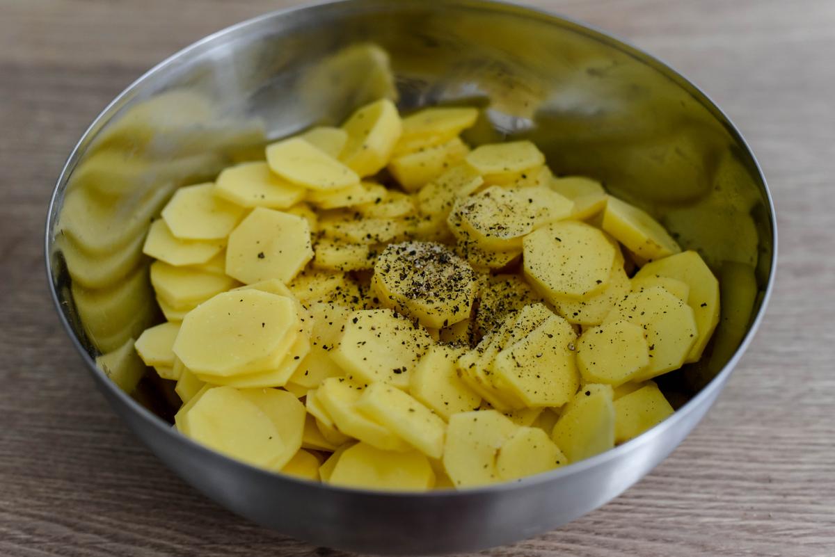 Place potato slices in a large bowl, season with salt and pepper, and toss to coat evenly. (Audrey Le Goff)