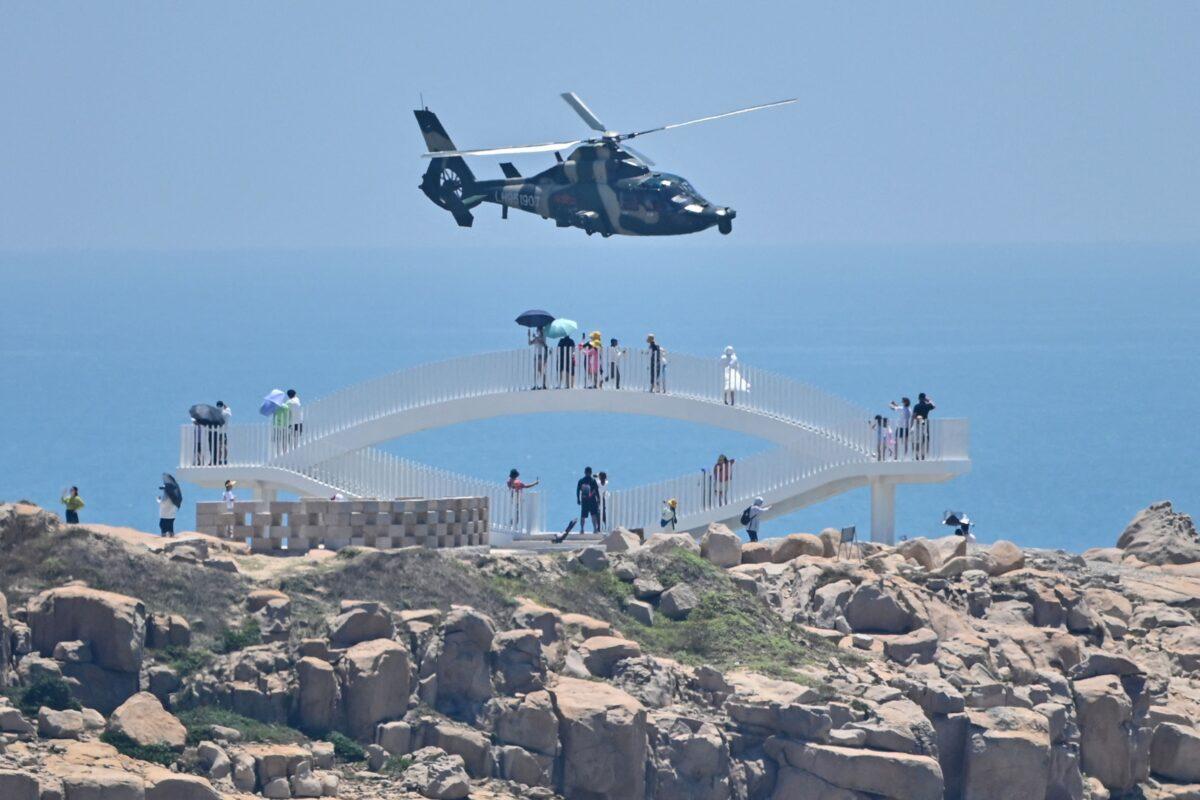 Tourists look on as a Chinese military helicopter flies past Pingtan Island, one of mainland China's closest points to Taiwan, in Fujian province on Aug. 4, 2022. (Hector Retamal/AFP via Getty Images)