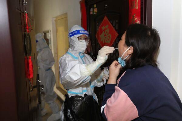 A medical worker takes a throat swab from a resident during door-to-door COVID-19 screening in Zhengzhou in central China's Henan Province on Nov. 1, 2022. (Chinatopix/Via AP)