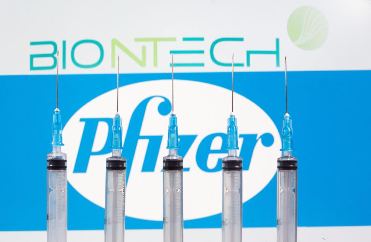 Syringes in front of displayed Biontech and Pfizer logos on Nov. 10, 2020. (Dado Ruvic/Illustration/Reuters)