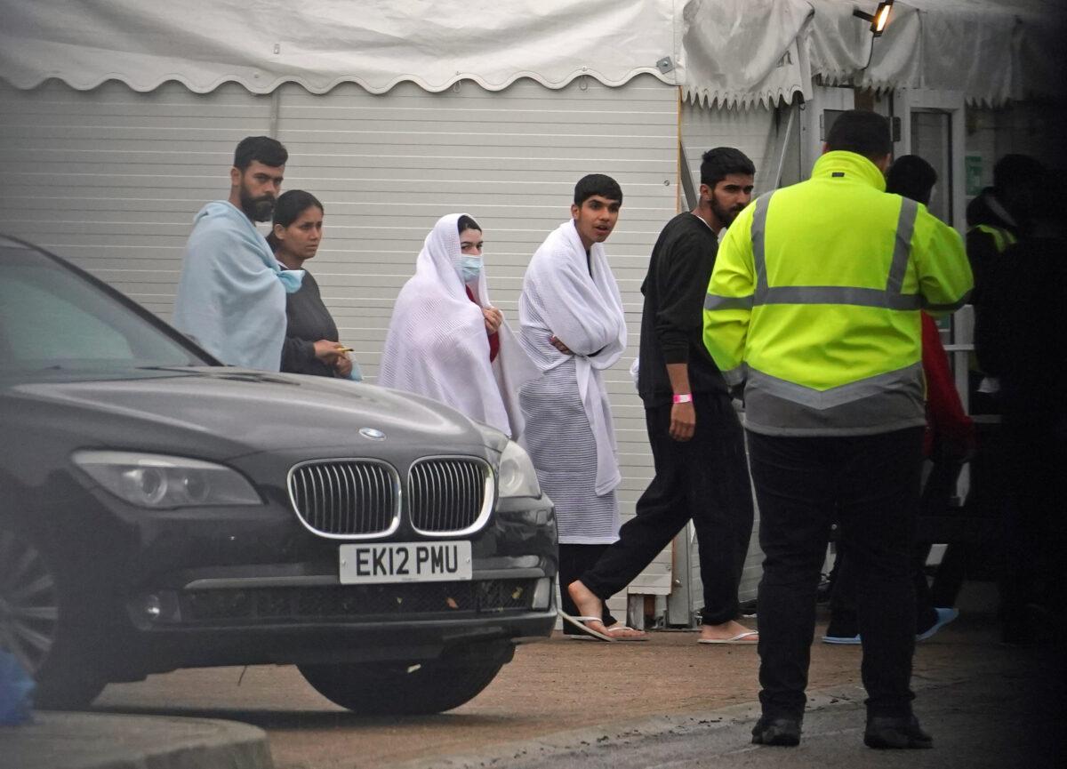 People thought to be illegal immigrants pass the car of Home Secretary Suella Braverman during her visit to the Manston migrant processing centre in Kent on Nov. 3, 2022. (PA Media)