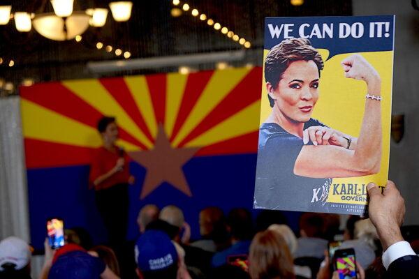 A voter holding a campaign sign listens as Arizona governor candidate Kari Lake speaks at a rally in Phoenix on Nov. 3, 2022. (Allan Stein/The Epoch Times)